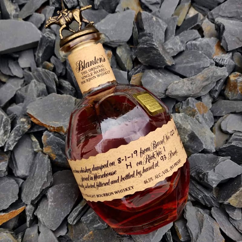 A bottle of Blanton's Single Barrel Bourbon sitting on purple slate